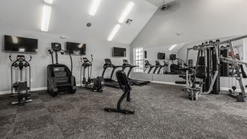 A spacious gym with a variety of equipment including treadmills, stationary bikes, and weight machines.